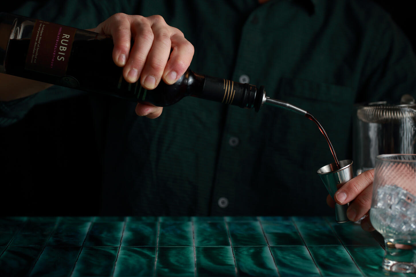 Bartender pouring Rubis wine in low light cocktail setting