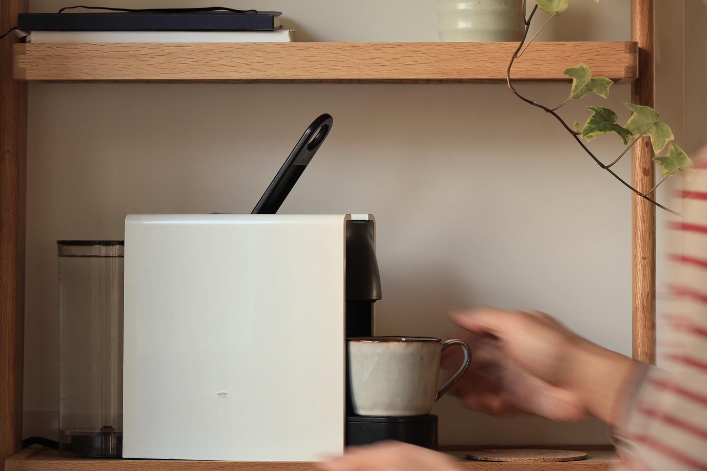 Nespresso coffee machine styled with cup and plants in warm natural kitchen setting