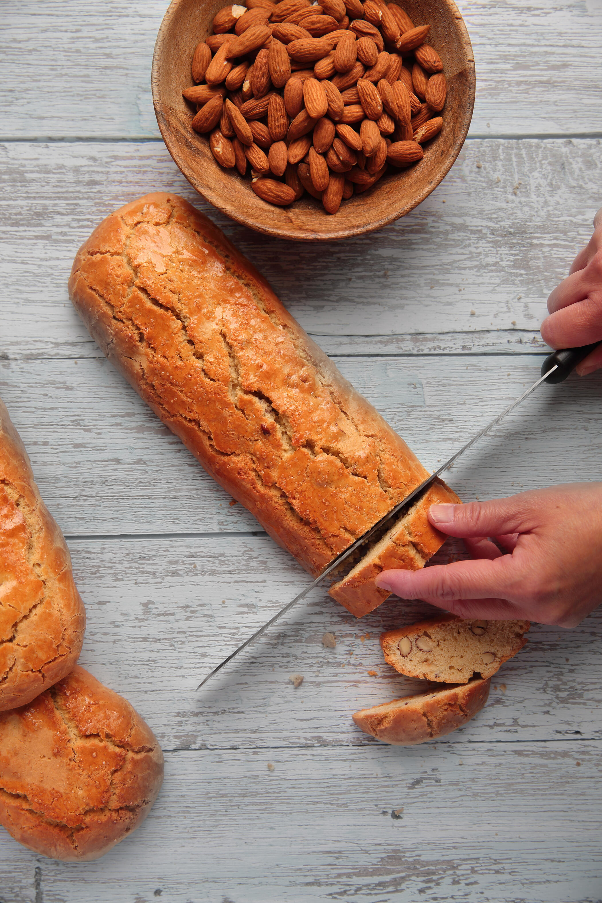 Cantuccini moment Flat lay of freshly baked cantuccini being sliced in soft natural light