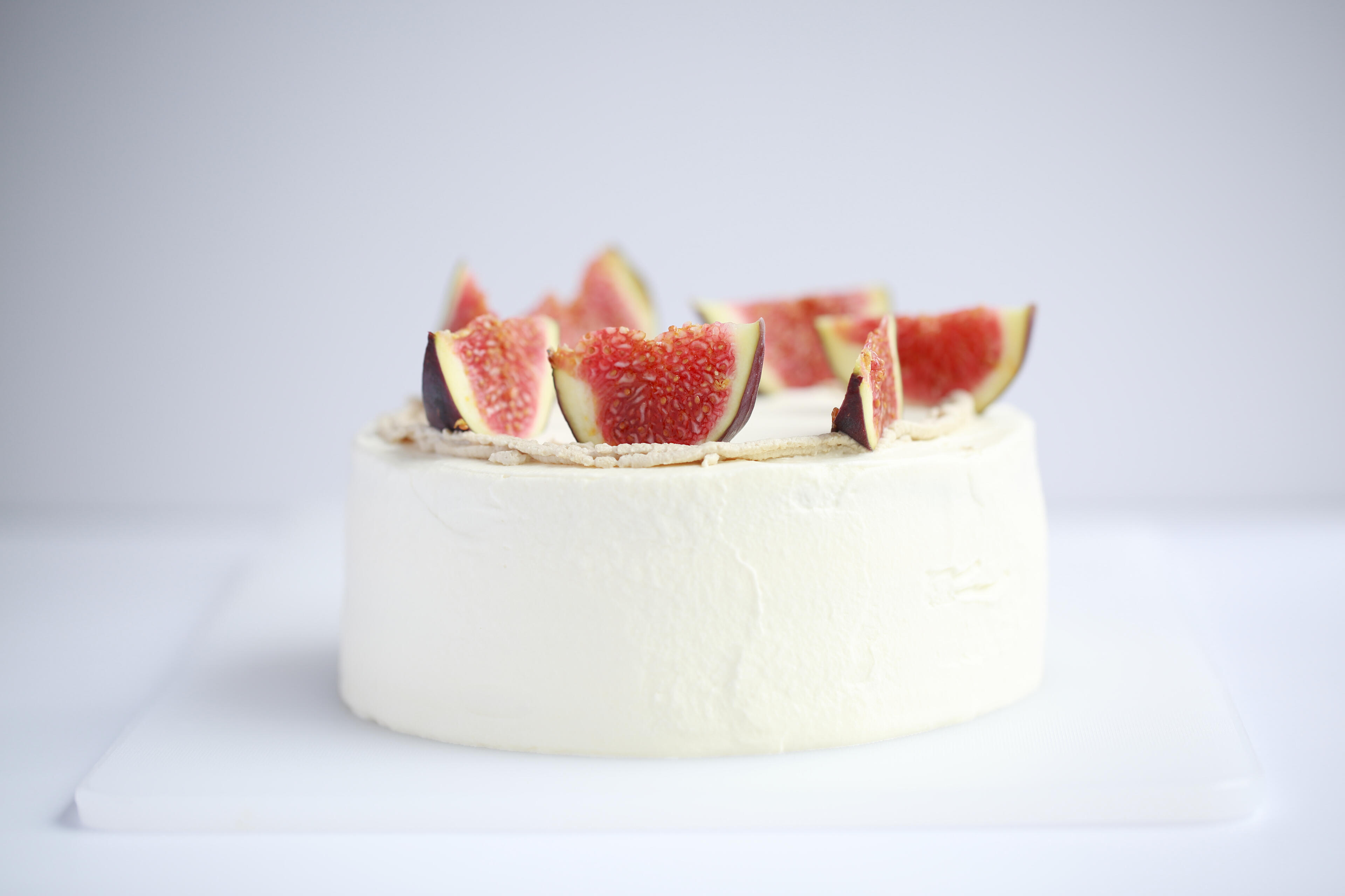 Elegant white fig cake photographed in minimal side lighting with clean background
