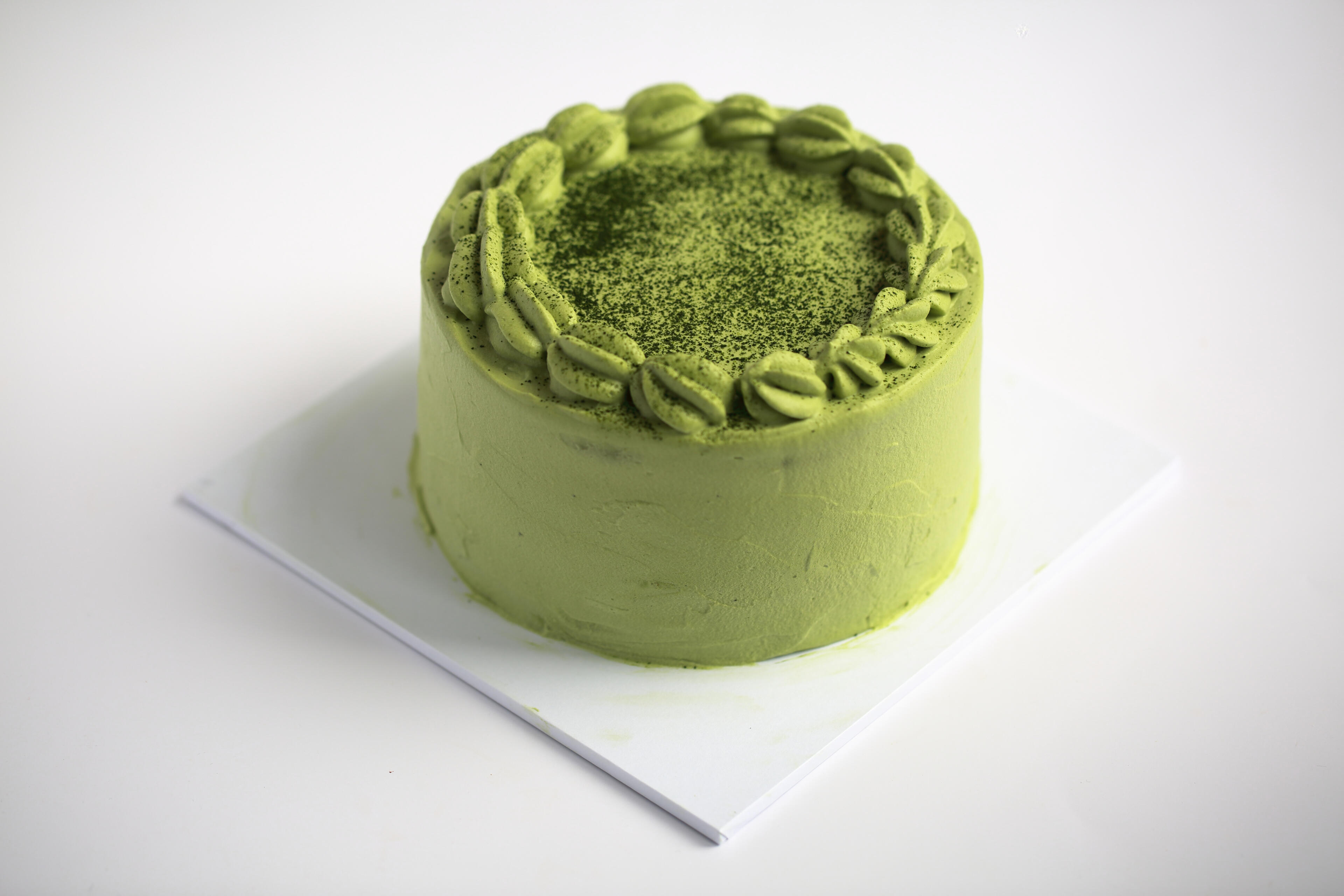 Minimal matcha cake Minimal white matcha cream cake styled with clean background and soft natural light for food photography in Horsham serving London and the South East
